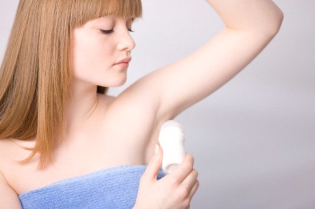 UK --- Close up of young woman applying deodorant under armpits --- Image by © Julian Winslow/ableimages/Corbis